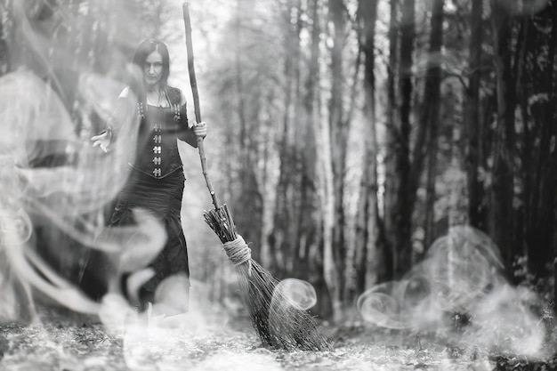 Une femme en costume de sorcière dans une forêt dense lors d'un rituel