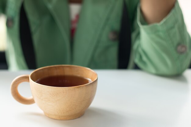 Femme en costume vert avec une tasse de thé chaud