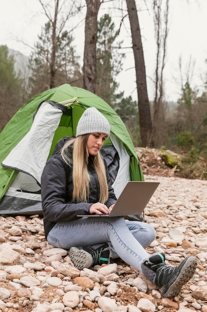 Femme à côté de la tente avec ordinateur portable