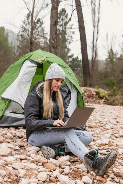 Femme à côté de la tente avec ordinateur portable