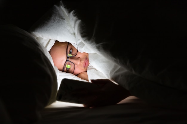 Femme Couchée Dans Son Lit à L'aide De Smartphone Tard Dans La Nuit. Insomnie, Nomophobie, Troubles Du Sommeil.