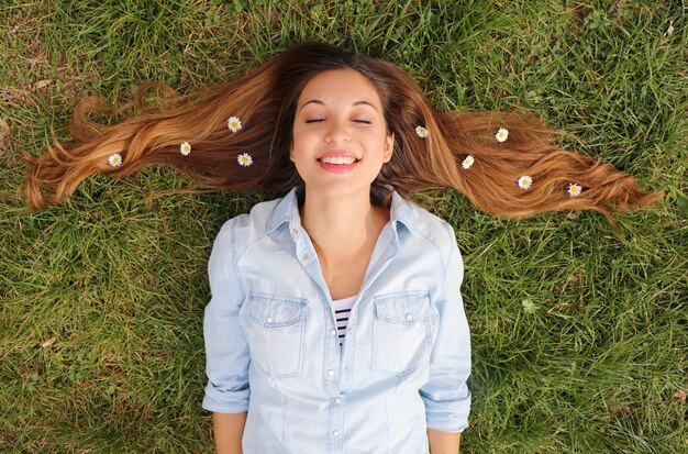 Femme couchée sur l'herbe avec des marguerites dans ses cheveux