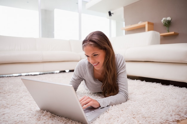 Femme couchée avec un ordinateur portable sur le tapis