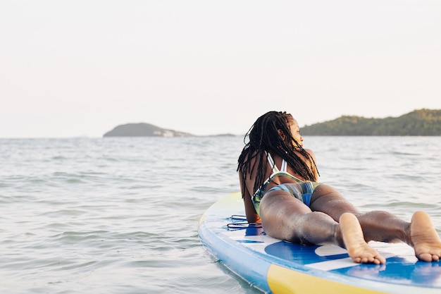 Femme couchée sur planche de surf sup