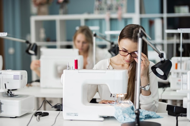 Une femme coud avec la machine à coudre électrique Atelier de tailleurs de mode