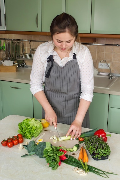 Femme coupant des légumes frais pour la salade dans la cuisine