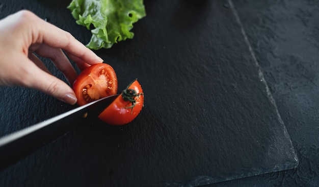 Femme coupant la tomate au couteau