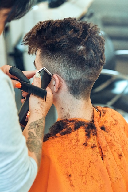 Photo une femme coupe les cheveux d'un homme dans un salon.