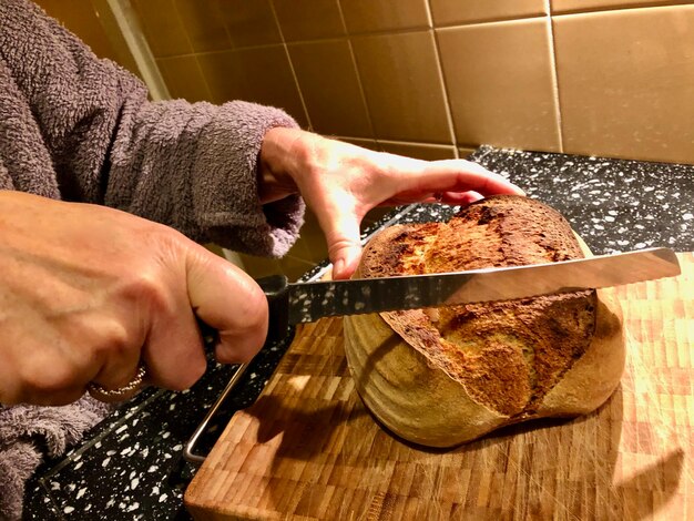 Une femme coupe du pain sur la table à la maison.