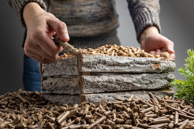 Une femme coupe une pile de vieilles briques de pierre avec un bâton au milieu.
