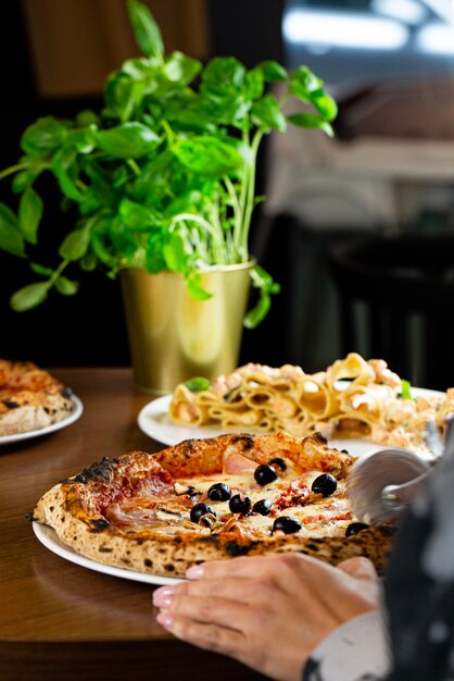 Photo une femme coupe une pizza