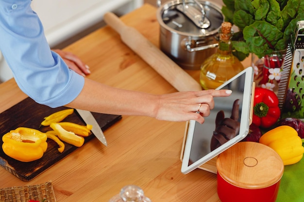 La femme coupe le poivron jaune pour la salade sur la table en bois