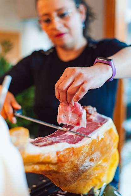 Une femme coupe de la viande sur une table avec un couteau.