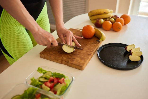 Femme coupée orange pour mélanger des jus de légumes et de fruits sains dans un mélangeur dans la cuisine