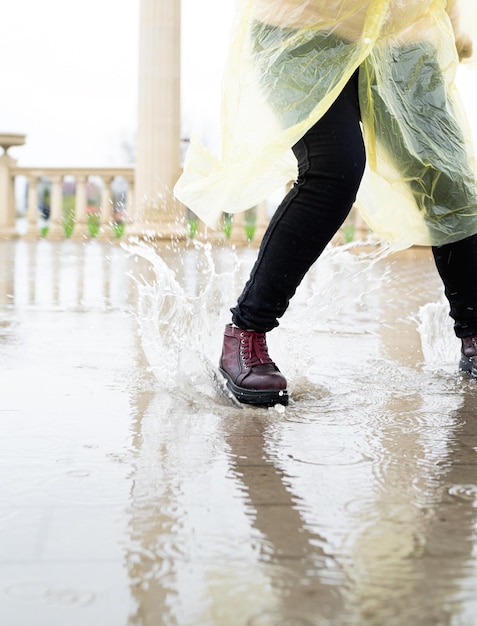 Photo femme courant sur l'asphalte par temps pluvieux en gros plan des jambes et des chaussures éclaboussées dans des flaques d'eau