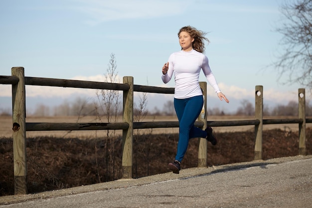 Photo femme courant sur la route contre le ciel