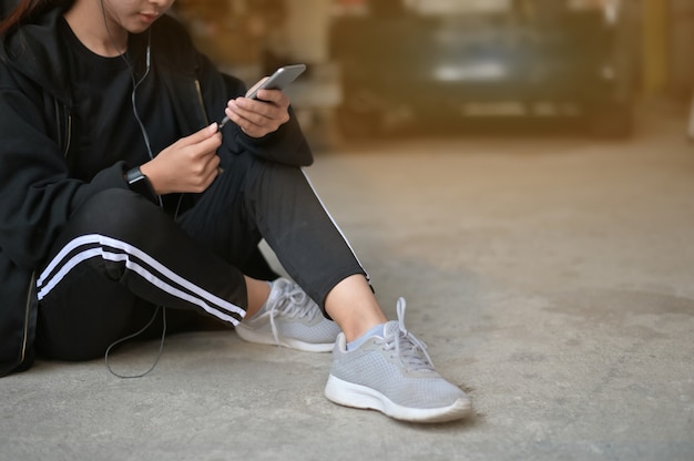 Femme de coureur à l&#39;aide d&#39;un téléphone portable avec oreille téléphone pré-courir sur le sol à la maison.