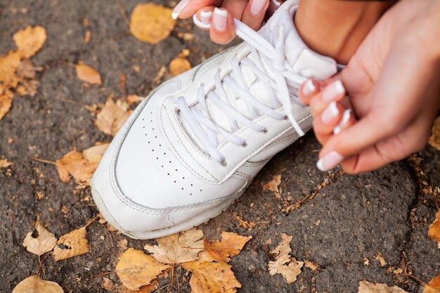 Femme, coureur, serrage, lacet, chaussure Coureur, femme, pieds, courant, route, gros plan, chaussure