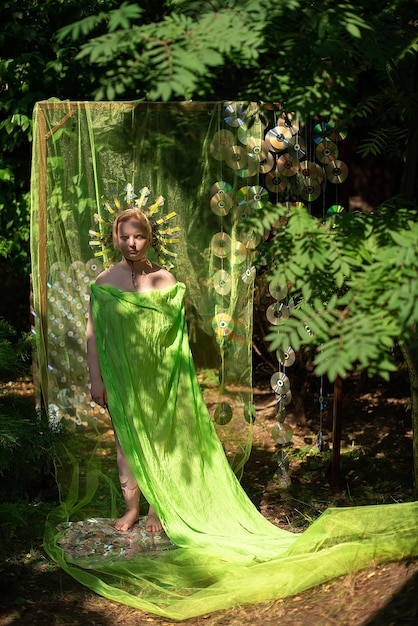 Photo une femme avec une couronne et une robe verte se tient comme une statue dans la forêt