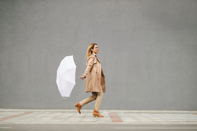 Une femme court dans les collines et tient son parapluie par temps de pluie