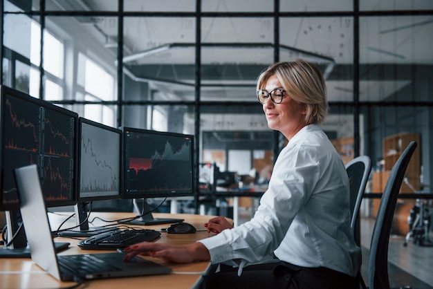 Une femme de courtage en vêtements formels travaille au bureau avec le marché financier.