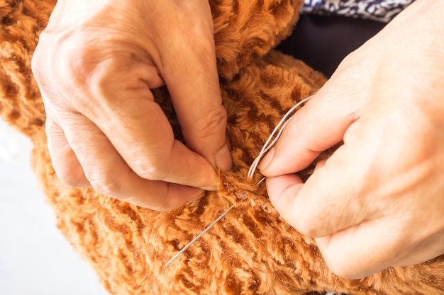 Femme cousant des ours en peluche, rénover une poupée cassée.