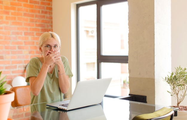 Femme couvrant la bouche avec les mains avec une expression choquée et surprise, gardant un secret ou disant oups