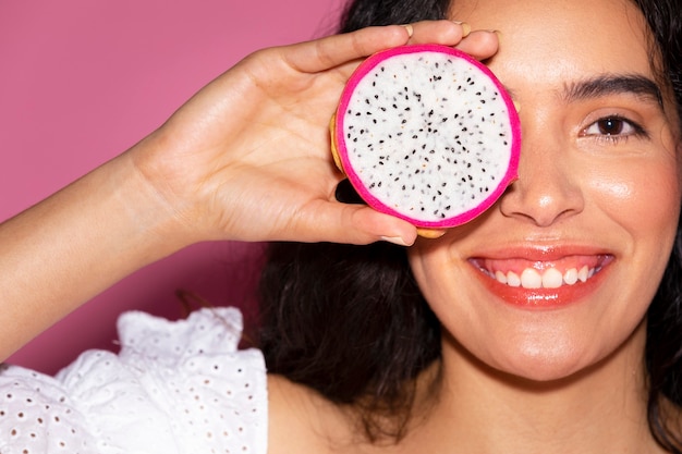 Femme couvrant ses yeux avec un fruit du dragon tranché