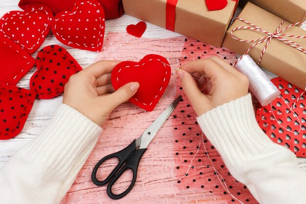 Femme créant un coeur rouge sur une table en bois. cadeau pour la Saint-Valentin à la main