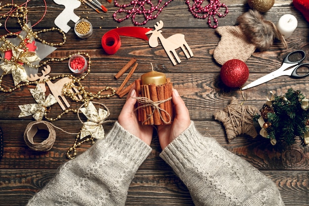 Femme créer des cadeaux de Noël élégants, décorer une bougie avec de la cannelle