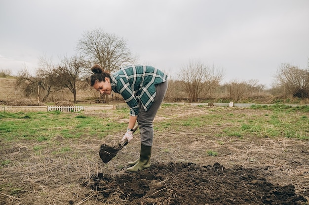 Une femme creuse la terre dans un champ Travaux agricoles au printemps dans le champ Préparation de la terre pour planter des moutons au printemps
