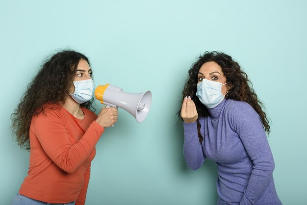 La femme crie avec haut-parleur à un ami mais il est difficile de comprendre avec un masque facial.