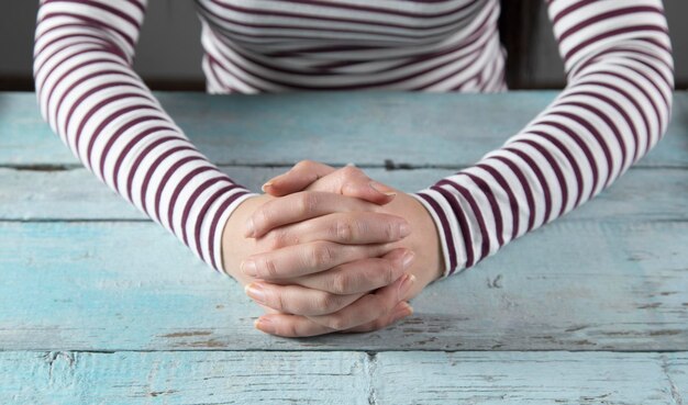 Femme croise le doigt sur la table