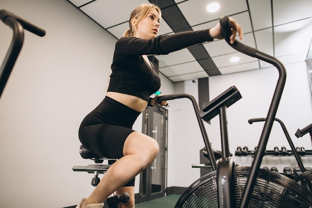 Femme Crossfit faisant un entraînement cardio intense sur un vélo d'exercice