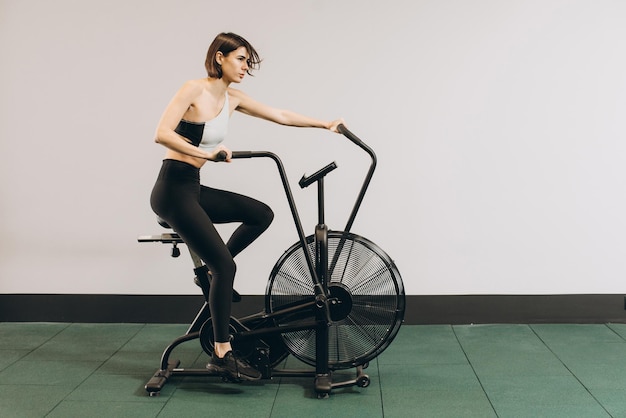 Femme Crossfit faisant un entraînement cardio intense sur un vélo d'exercice