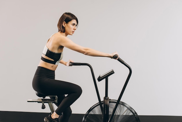 Femme Crossfit faisant un entraînement cardio intense sur un vélo d'exercice