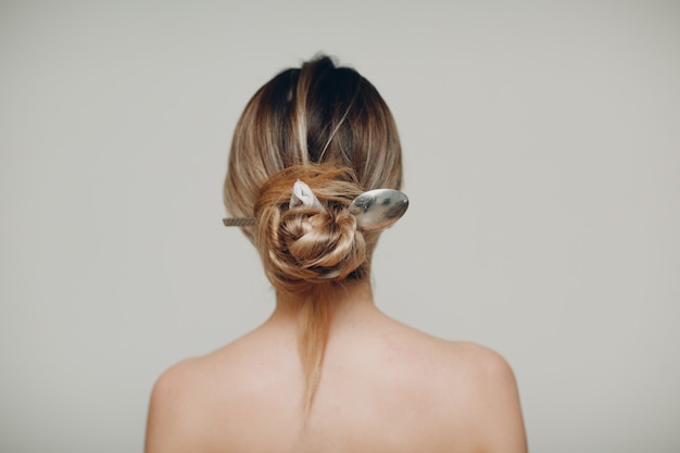 Femme avec une cuillère en métal dans sa coiffure cheveux en arrière