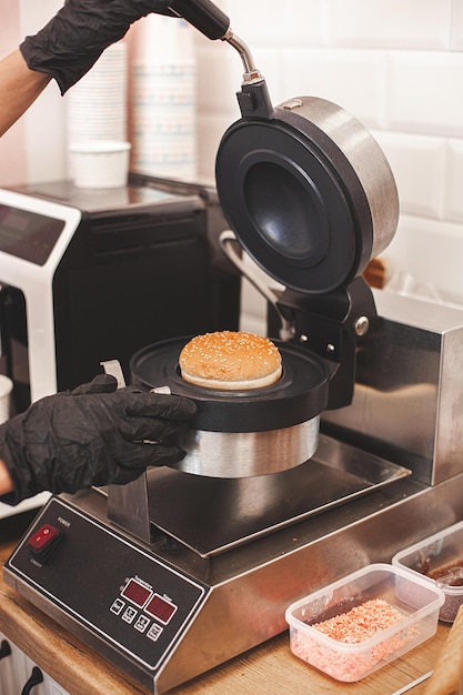 Femme cuisinant un hamburger au restaurant Équipement professionnel de cuisine pour faire des hamburgers