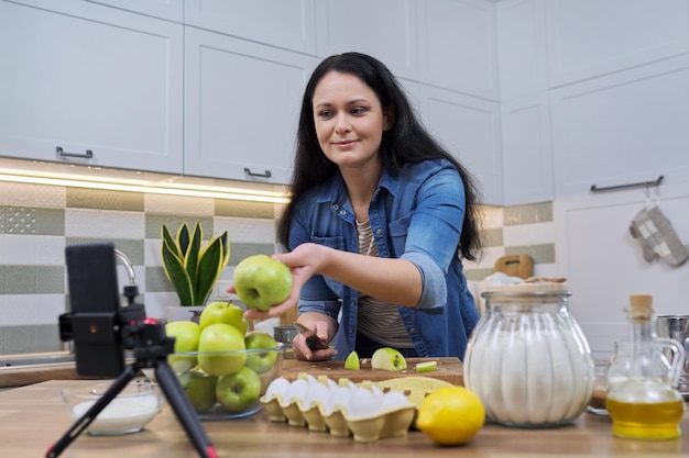 Femme cuisinant à la maison dans la cuisine parlant en ligne à l'aide d'un appel vidéo sur smartphone