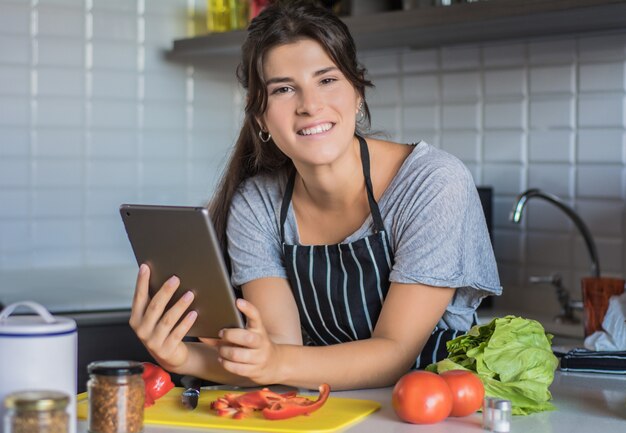 Femme cuisine et recette suivante sur tablet pc