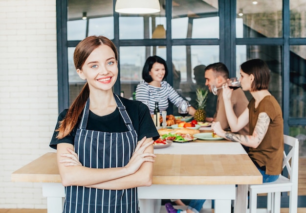 Femme cuisinier sur le fond d'une fête avec des gens dans la cuisine dans un appartement