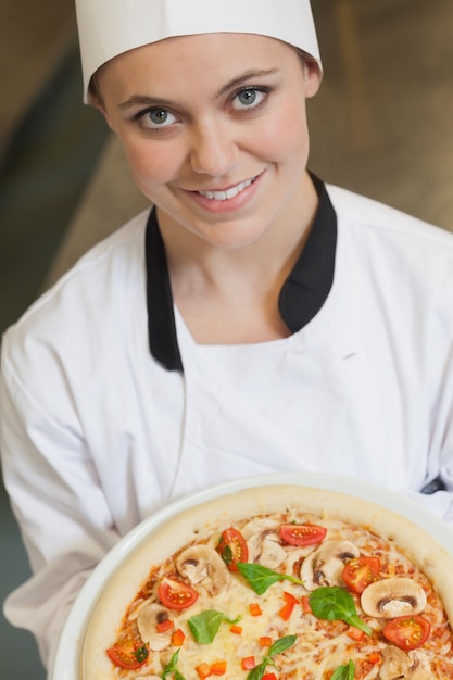 Femme cuisinier tenant une pizza