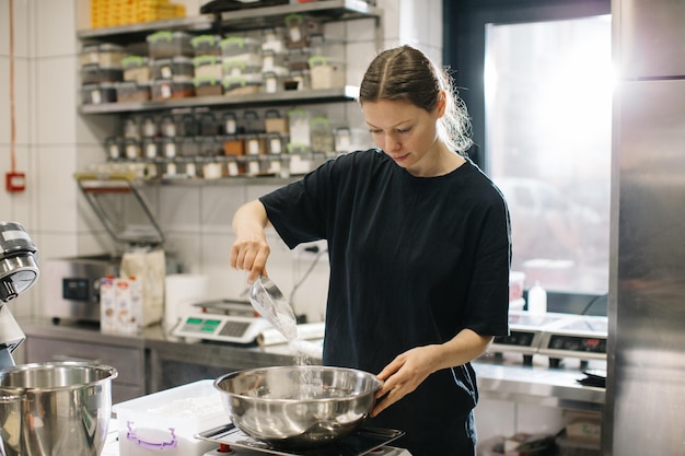 Une femme cuisinière travaille dans une cuisine industrielle moderne Le processus de fabrication de gâteaux dans une boulangerie ou un café