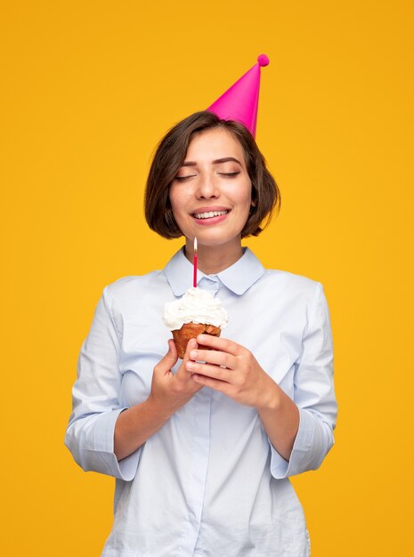 Femme avec cupcake d'anniversaire faisant un vœu