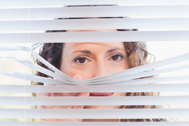 Femme curieuse regardant à travers les stores