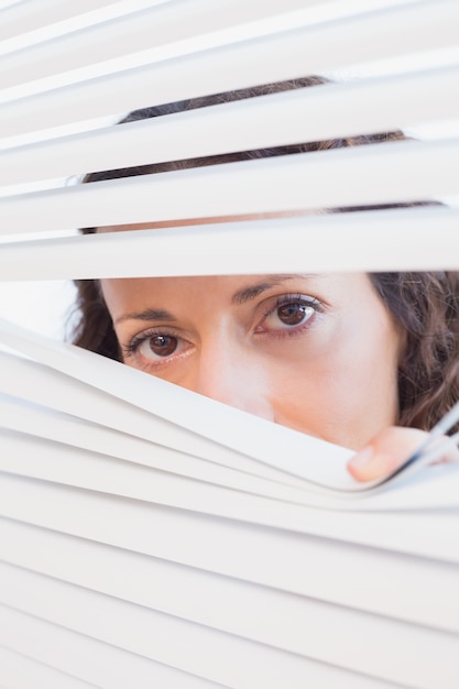 Femme curieuse regardant à travers les stores