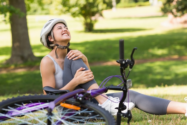 Femme cycliste avec jambe blessée, assis dans le parc