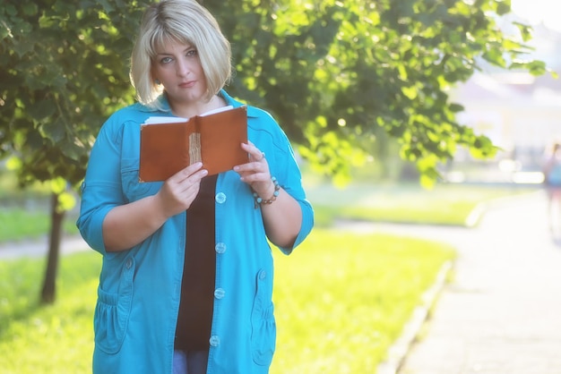 Femme dans l'arbre vert du parc avec livre