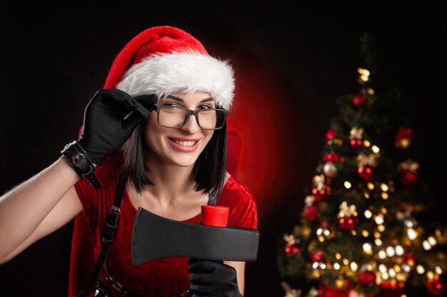 Une femme dans un body de Noël rouge et un bonnet de Noel avec une hache