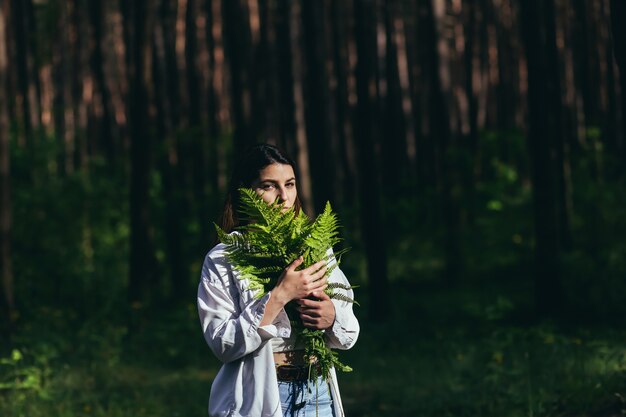 Une femme dans les bois embrasse un bouquet de fougères, un jeune militant protège la forêt